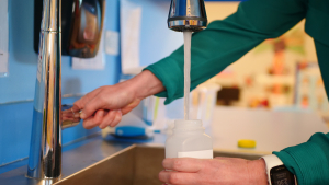 child care provider collecting water sample at faucet