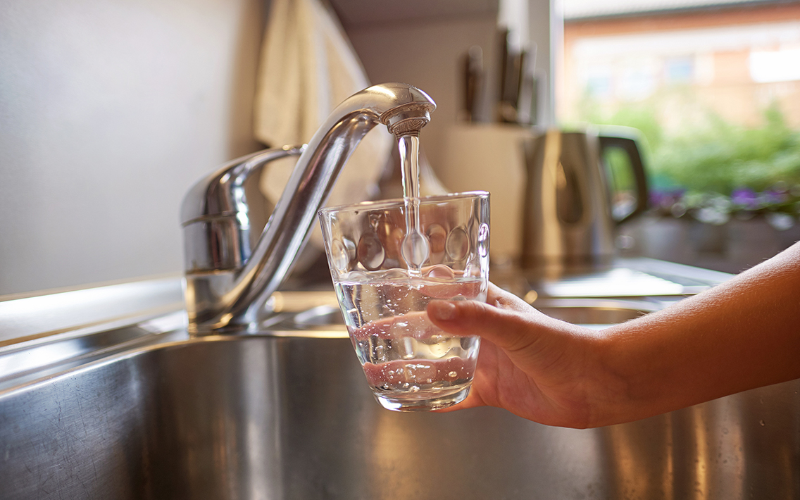 child care provider pouring water from kitchen sink faucet